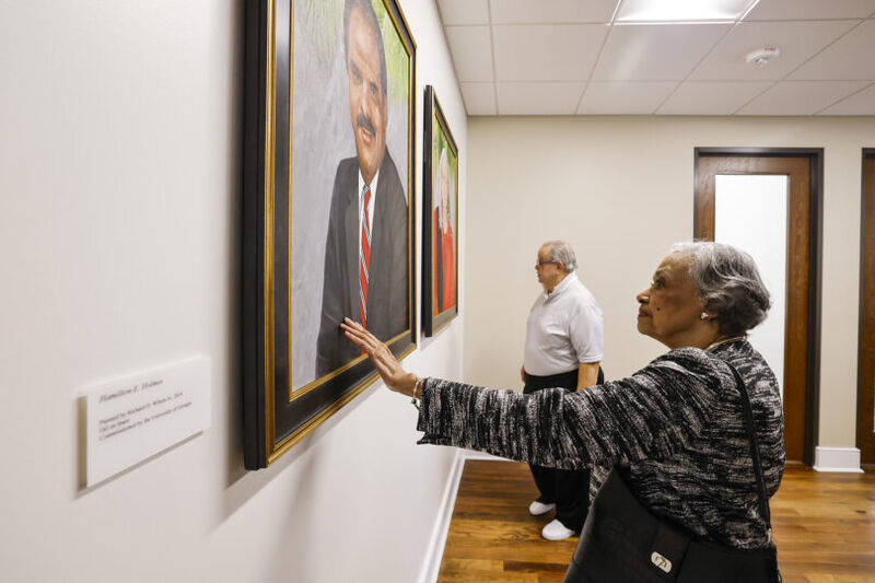 Charlayne Hunter-Gault touching a portrait of Hamilton Holmes